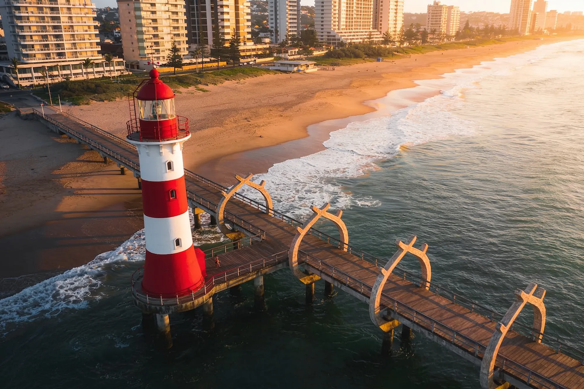 The red-and-white Umhlanga lighthouse and the Whalebone Pier on the beach